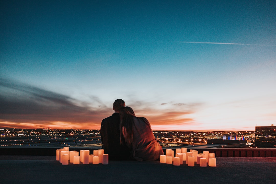 Two people sitting behind glowing candles overlooking a city at night